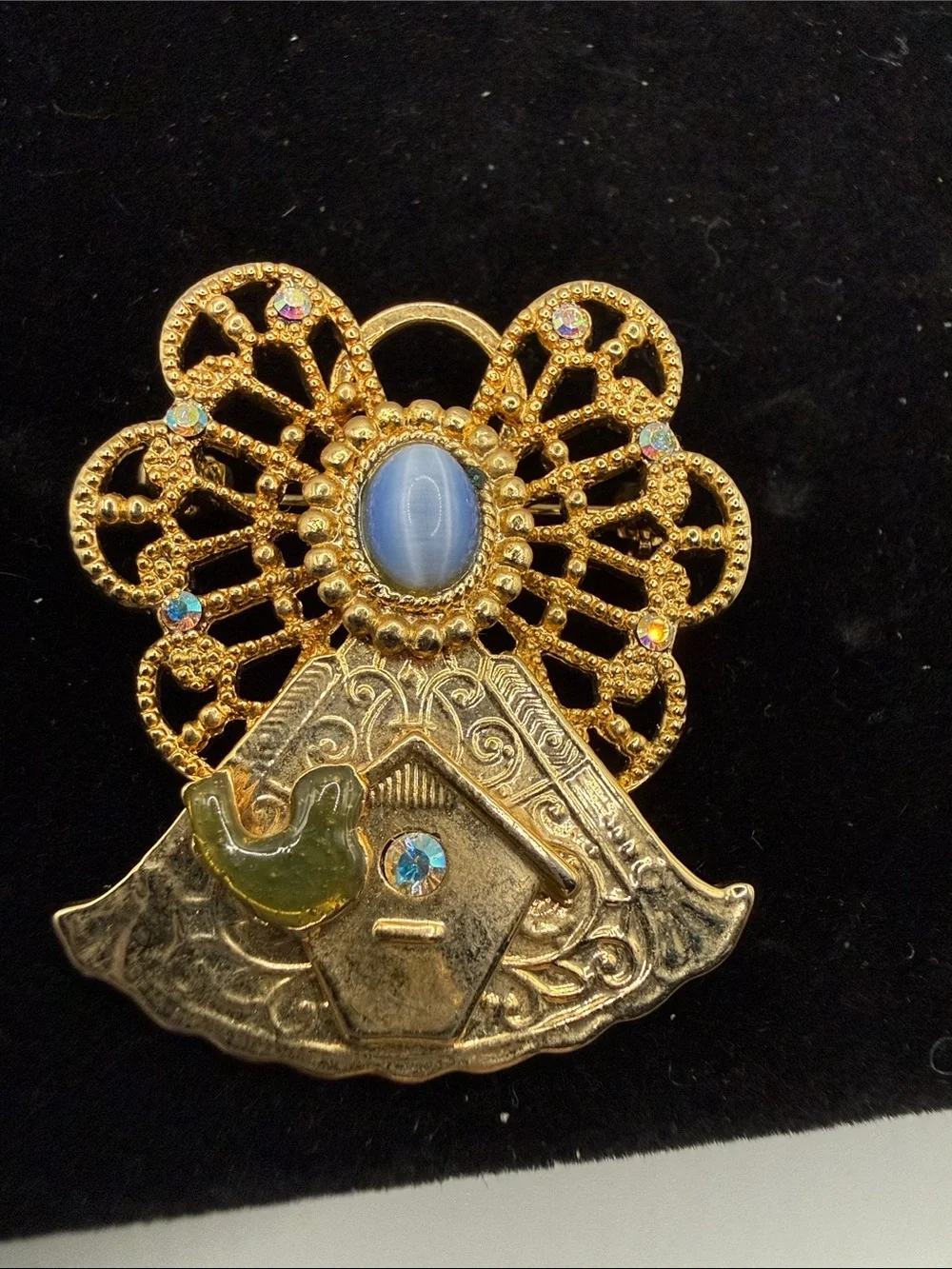 vintage gold-tone angel brooch features a filigree halo, a blue cabochon stone…